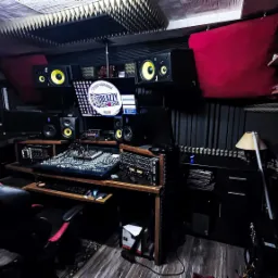 Profesjonalne pomieszczenie z panelami akustycznymi, mikserem dźwięku, monitorami studyjnymi i komputerem z logo 'Creazzy Records'.