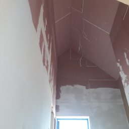 P.H.U. Dr Volt Zbigniew Frejman - Poddasze po montażu płyt gipsowo-kartonowych i częściowym szpachlowaniu. Widoczne kable elektryczne zwisające z sufitu. Okno zabezpieczone folią.