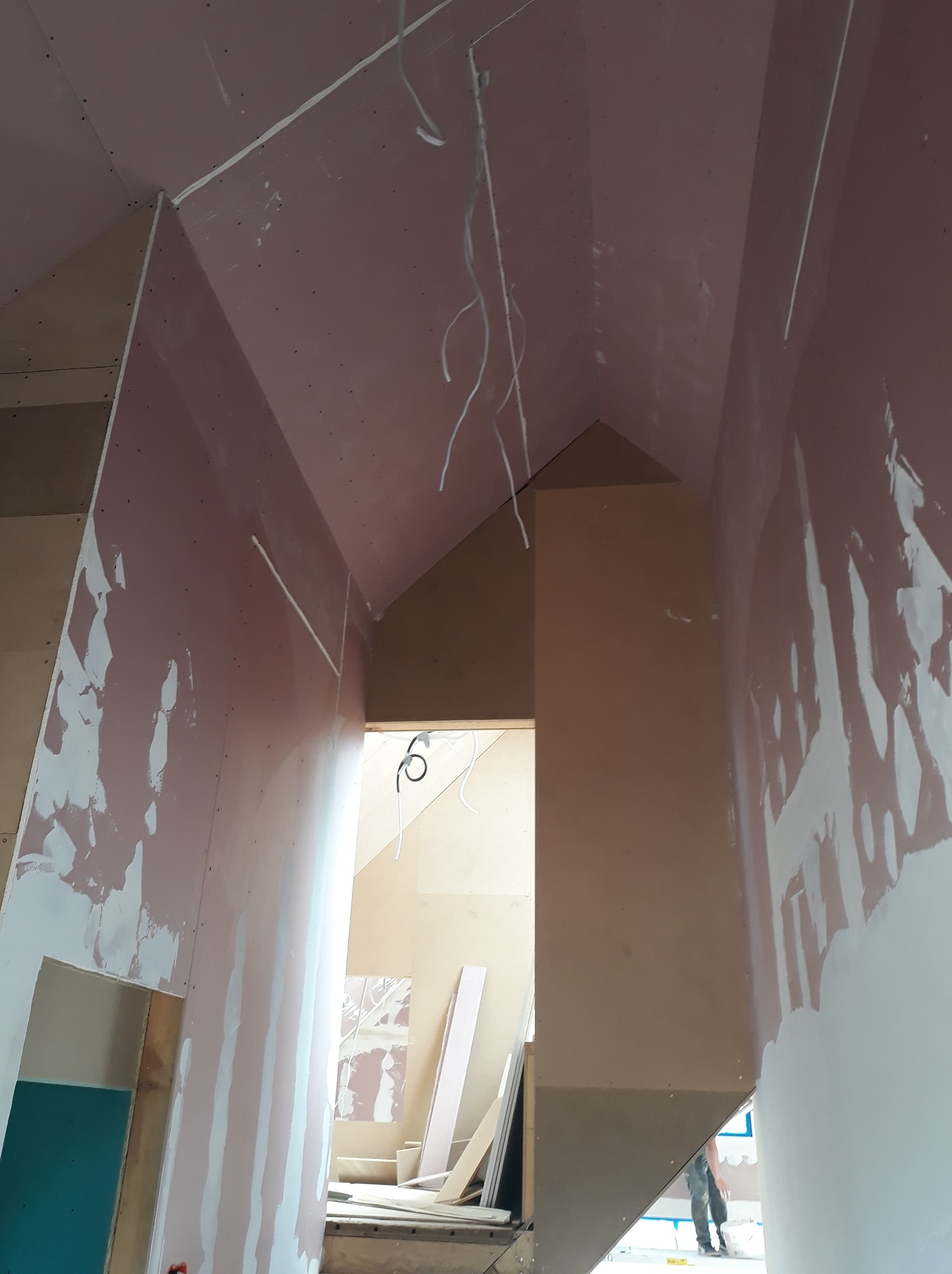 Wnętrze w trakcie remontu: ściany z płyt gipsowo-kartonowych, częściowo zaszpachlowane, widoczne przewody elektryczne i konstrukcja poddasza.