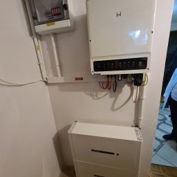 freeDOM fotowoltaika Marcin Szałacki - Wnętrze z zamontowanym inwerterem i magazynem energii GoodWe na ścianie, widoczne okablowanie i skrzynka rozdzielcza AC. Instalacja w pomieszczeniu.