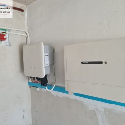 freeDOM fotowoltaika Marcin Szałacki - Zamontowana instalacja fotowoltaiczna wewnątrz budynku. Widoczne inwertery GoodWe i zabezpieczenia elektryczne. Montaż na niebieskiej listwie.