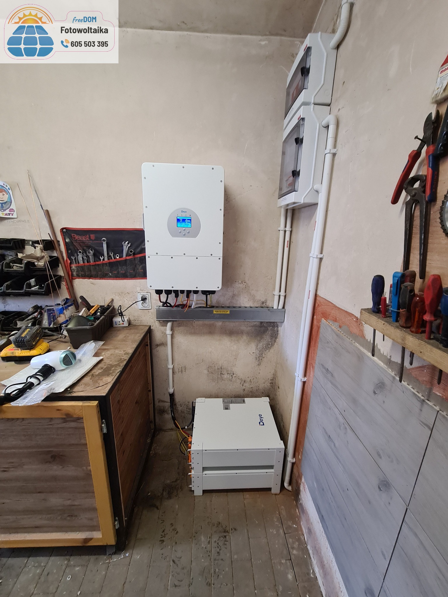 Montaż inwertera i magazynu energii w pomieszczeniu gospodarczym. Widoczne przewody, skrzynki elektryczne i narzędzia.