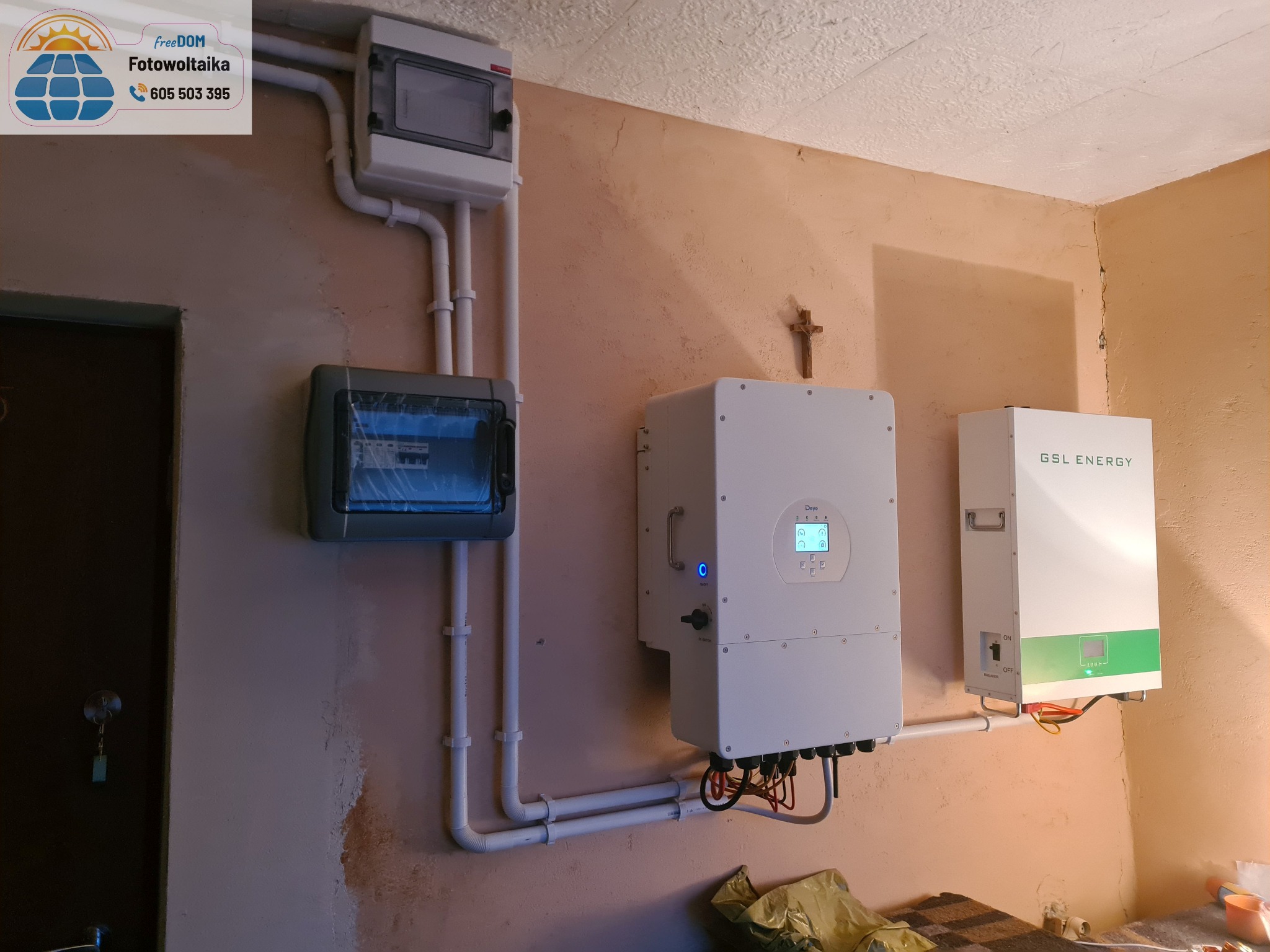 Instalacja fotowoltaiczna wewnątrz budynku: rozdzielnice, inwerter Deye i magazyn energii GSL Energy, z widocznymi przewodami i rurami instalacyjnymi.