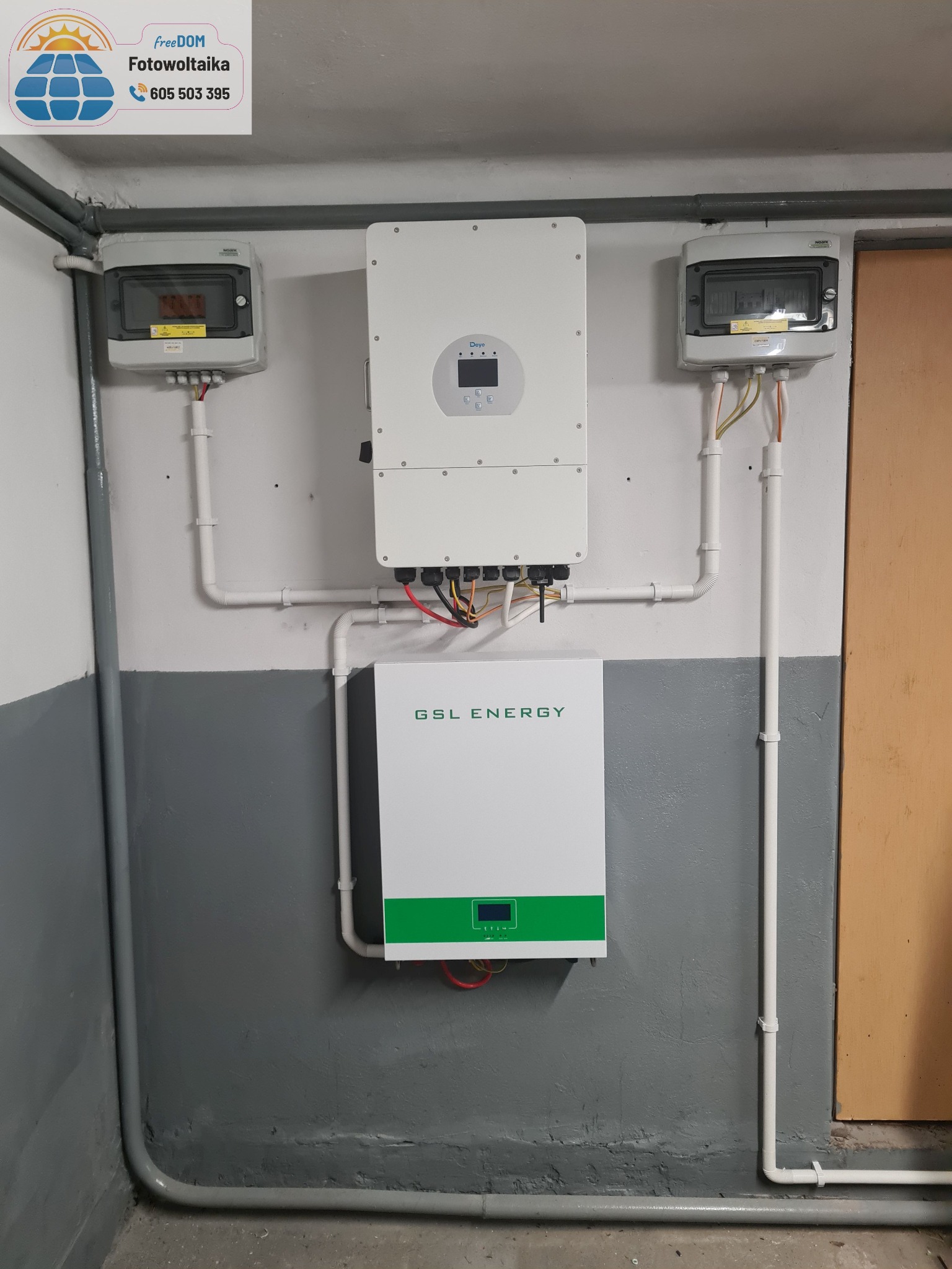 Instalacja fotowoltaiczna w piwnicy: dwa rozdzielacze, inwerter i magazyn energii GSL Energy, białe rury na tle szarej ściany.
