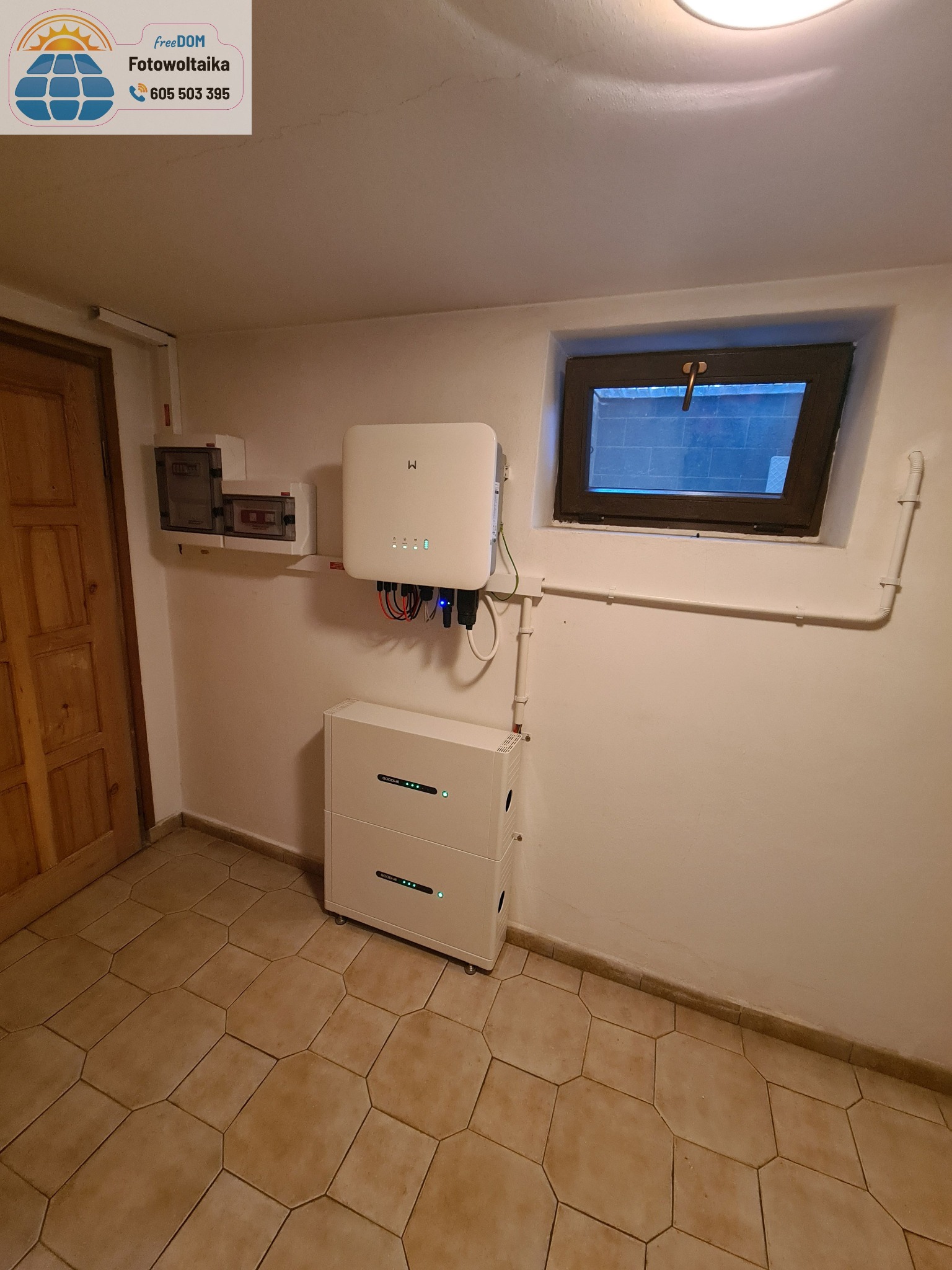 Kompletna instalacja fotowoltaiczna w piwnicy: inwerter GoodWe, dwuczęściowy magazyn energii, rozdzielnia elektryczna i okno piwniczne w tle.