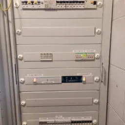 Rozdzielnica elektryczna w obudowie, widoczne zabezpieczenia różnicowoprądowe, wyłączniki nadprądowe i moduł KNX GIRA EIB, z opisami obwodów: halogeny, brama, domofon, rezerwa, gniazda...