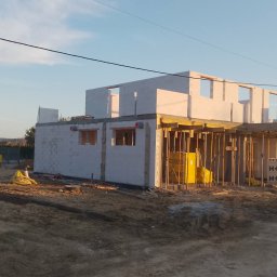 Salwa Budownictwo - Budowa domu z betonu komórkowego: ściany parteru i szalunek stropu w trakcie realizacji. Widoczne bloczki H+H, teren budowy i zaparkowany samochód osobowy.