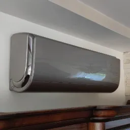 Elegancki klimatyzator w kolorze grafitowym zamontowany na ścianie, widoczny fragment dekoracyjnego kominka i ściana wyłożona kamieniem.