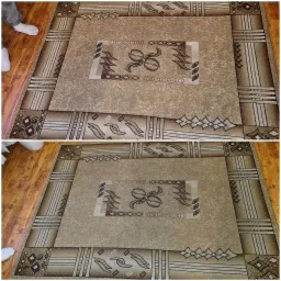 Beżowy dywan z geometrycznym wzorem i elementami roślinnymi, widok z góry, z fragmentem drewnianej podłogi i stopami w białych skarpetkach.