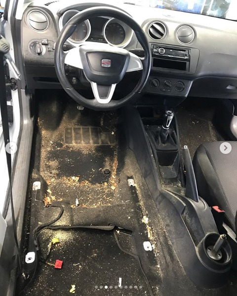Wnętrze brudnego samochodu marki Seat przed czyszczeniem, widoczne zdemontowane fotele i zabrudzona podłoga.