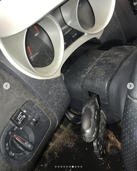 Wnętrze samochodu z widocznymi elementami deski rozdzielczej, kierownicy i przełączników, silnie zabrudzone kurzem i innymi zanieczyszczeniami.