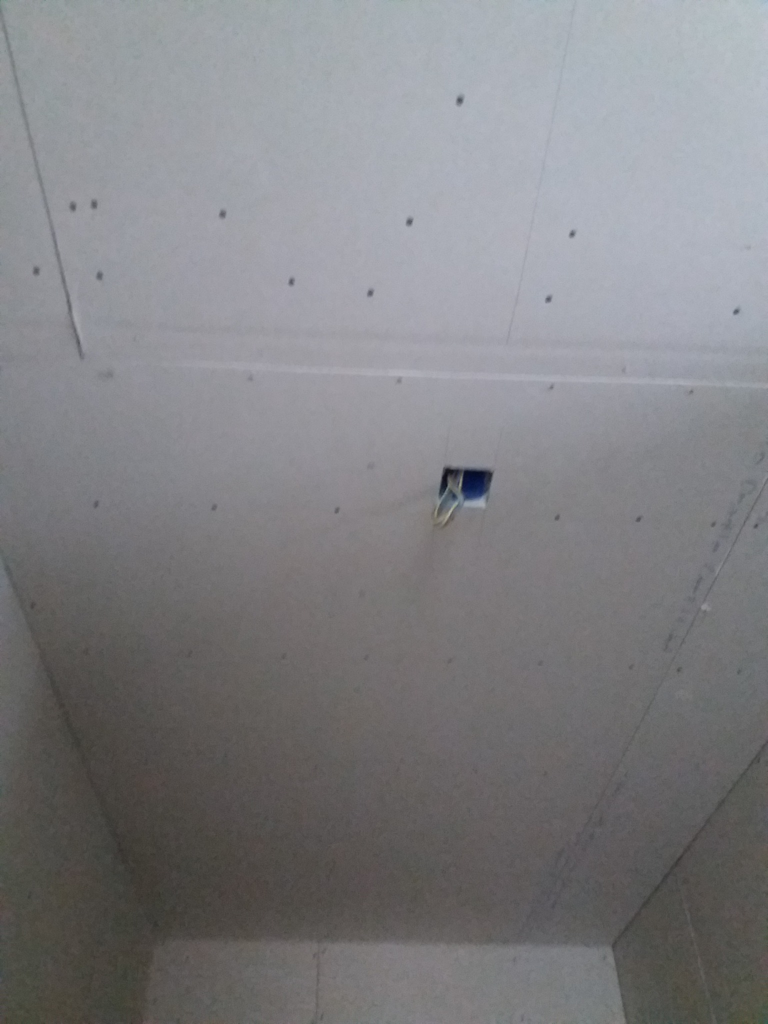 Montaż sufitu z płyt gipsowo-kartonowych z widocznym otworem na instalację elektryczną, mocowany na metalowym stelażu.