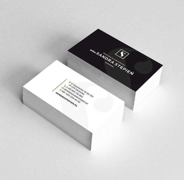 Stos wizytówek adwokata Sandry Stępień, z czarnym tłem na górnej wizytówce, prezentujące logo i dane kontaktowe.