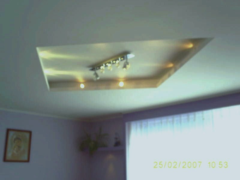 Podwieszany sufit z oświetleniem halogenowym, widoczne wykończenie glazurnicze w postaci obramowania wnęki sufitowej, ściany w kolorze liliowym.