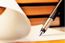 Pióro wieczne na otwartej książce z kremowymi kartkami, w tle stos książek o ciepłych barwach.