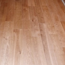 Wiesław Hojdak - Nowo położona, jasna podłoga z paneli imitujących drewno, widoczne niedomalowane ściany i futryny w tle.