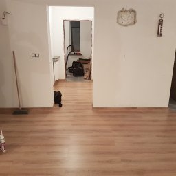 Wiesław Hojdak - Wnętrze w trakcie remontu: świeżo położona podłoga z paneli, widoczne tuby z klejem, przygotowane do dalszych prac wykończeniowych, ściany wymagające odświeżenia, widoczne ślady po instalacjach...