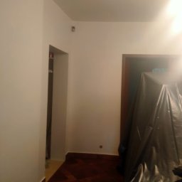 Wiesław Hojdak - Wnętrze w trakcie odświeżania: pomalowane na biało ściany, zabezpieczone folią meble i parkiet z ciemnego drewna.