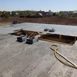 Wylewka fundamentowa w trakcie realizacji we Wrocławiu, widoczne otwory na instalacje, żółty wąż do pompy betonu i bloczki betonowe.