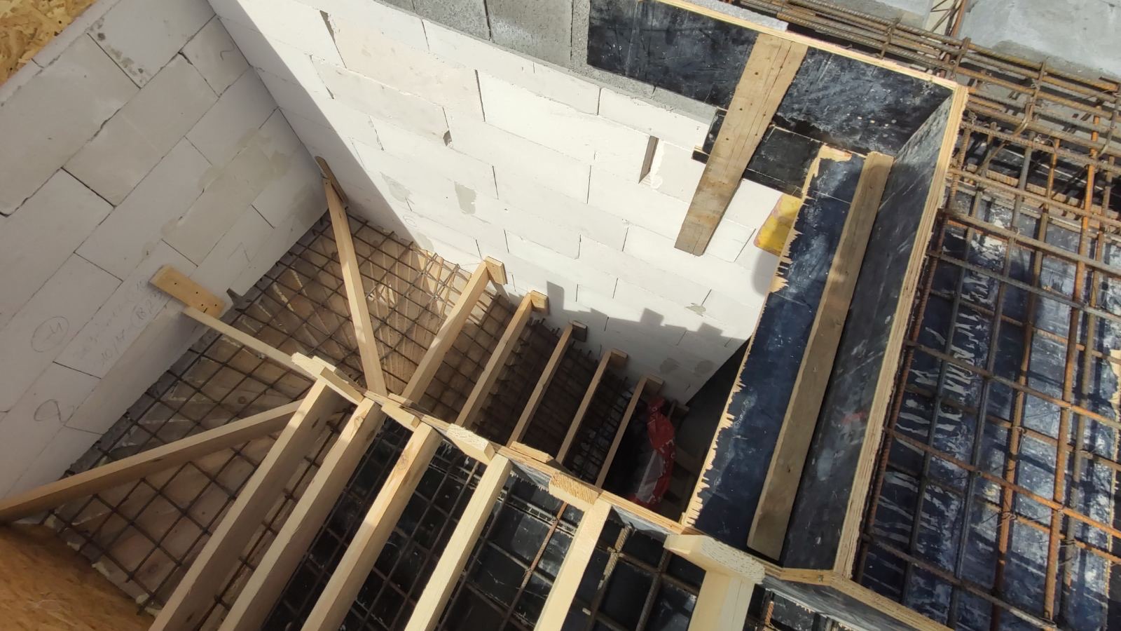 Wewnętrzna konstrukcja szalunku schodów zbrojonych, widok z góry, z elementami muru z bloczków betonu komórkowego.