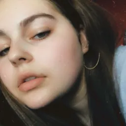 Portret młodej kobiety z kolczykiem kołem, skierowanej w dół, z efektem vintage i drobnymi zarysowaniami na zdjęciu.