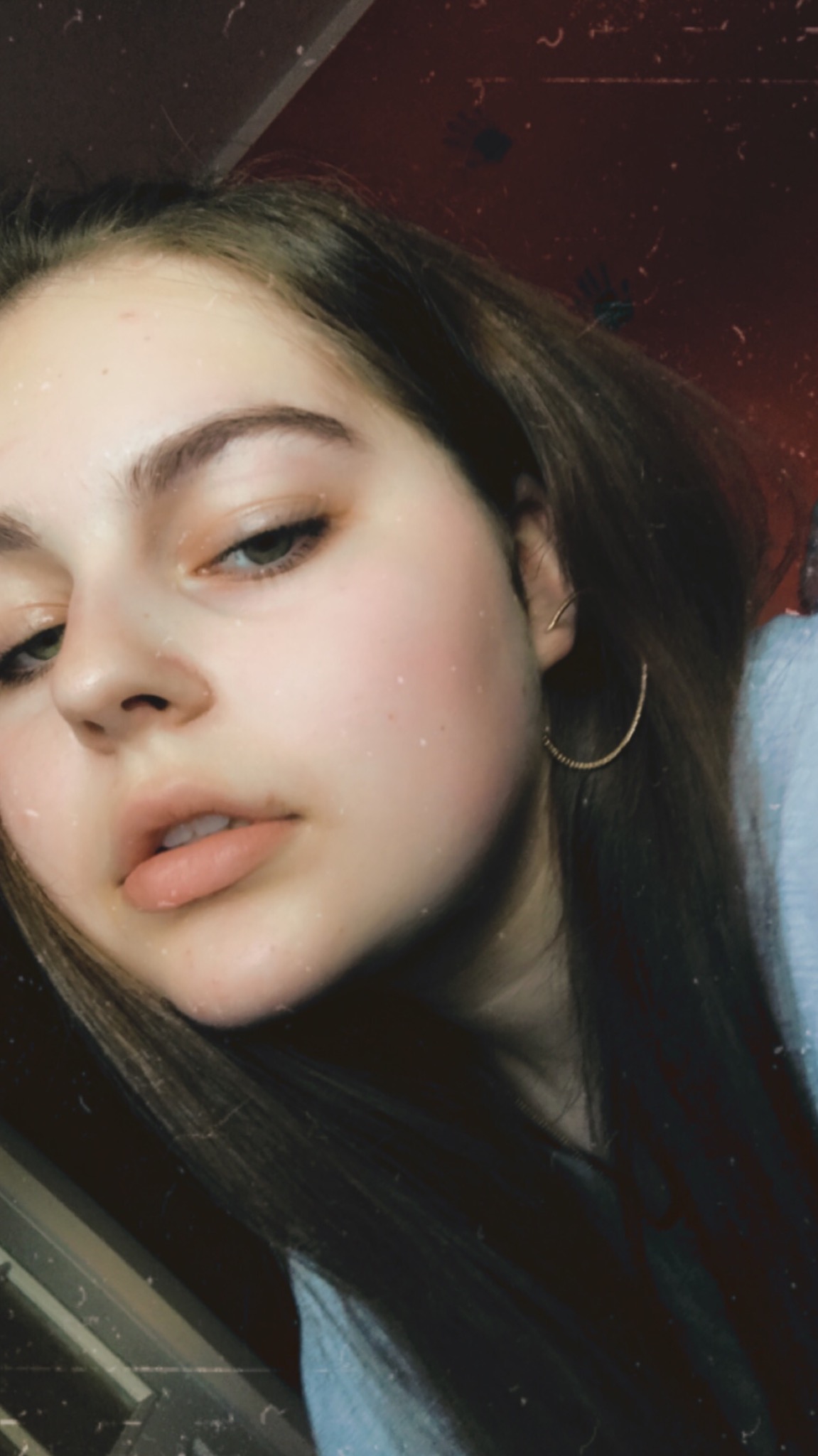 Portret młodej kobiety z kolczykiem kołem, skierowanej w dół, z efektem vintage i drobnymi zarysowaniami na zdjęciu.