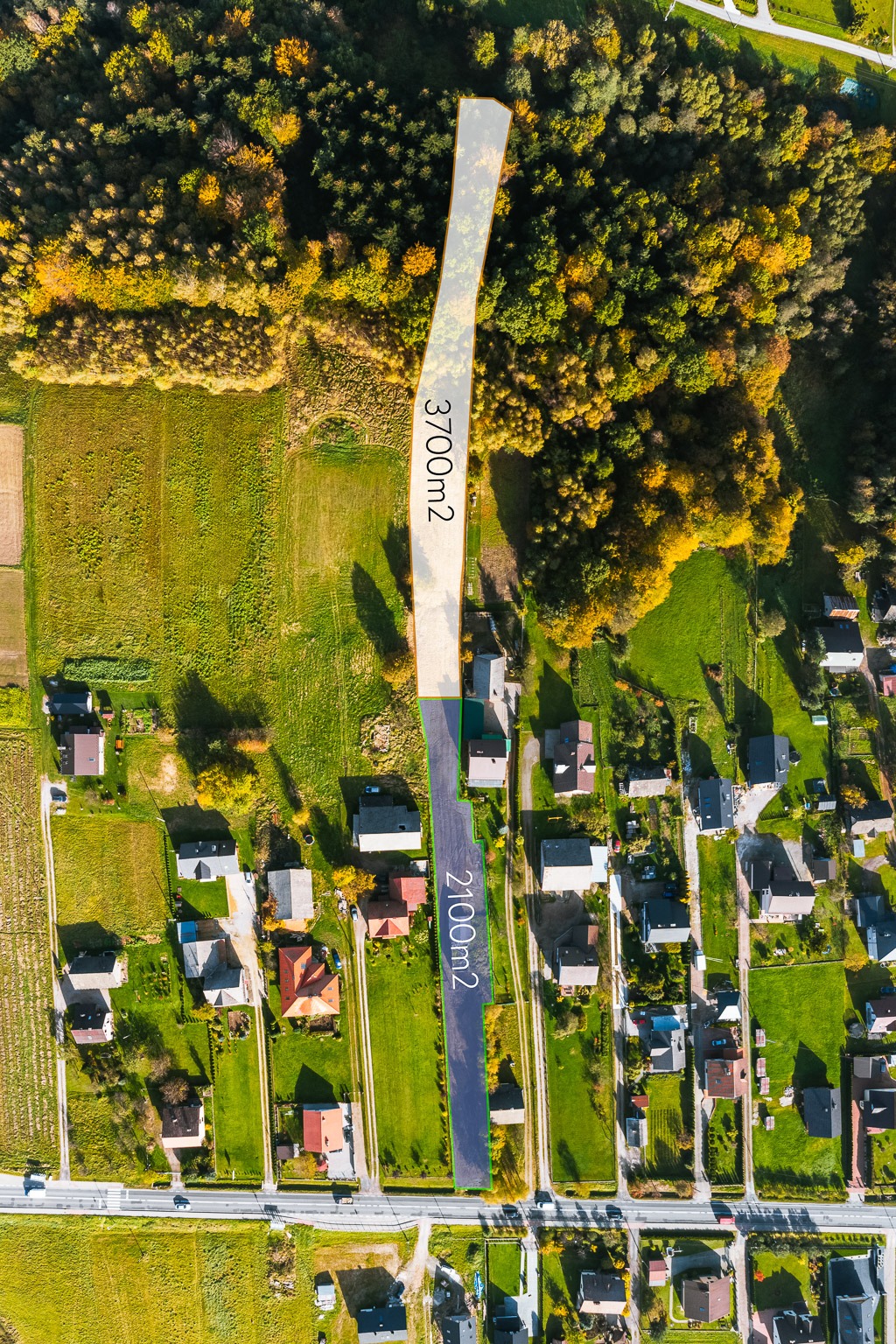 Zdjęcie lotnicze dwóch działek budowlanych o powierzchni 3700m2 przylegającej do lasu i 2100m2 w zabudowie jednorodzinnej, widok z góry w słoneczny dzień.