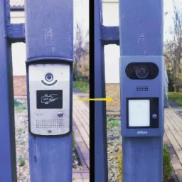 Porównanie starego i nowego domofonu na metalowej bramie, z żółtą strzałką wskazującą na wymianę urządzenia.