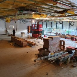 G&K Stroi - Wnętrze biura w Gdańsku w trakcie remontu, widoczna podwieszana konstrukcja sufitu, instalacje, podnośnik i materiały budowlane.