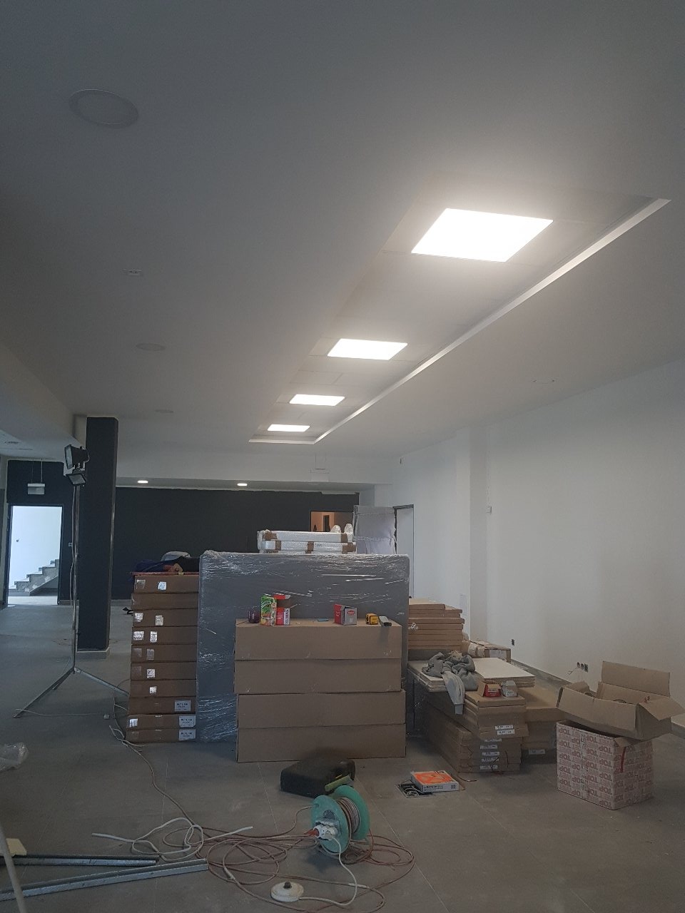 Montaż sufitu z wbudowanymi panelami LED w trakcie prac wykończeniowych, widoczne materiały budowlane i narzędzia na podłodze.