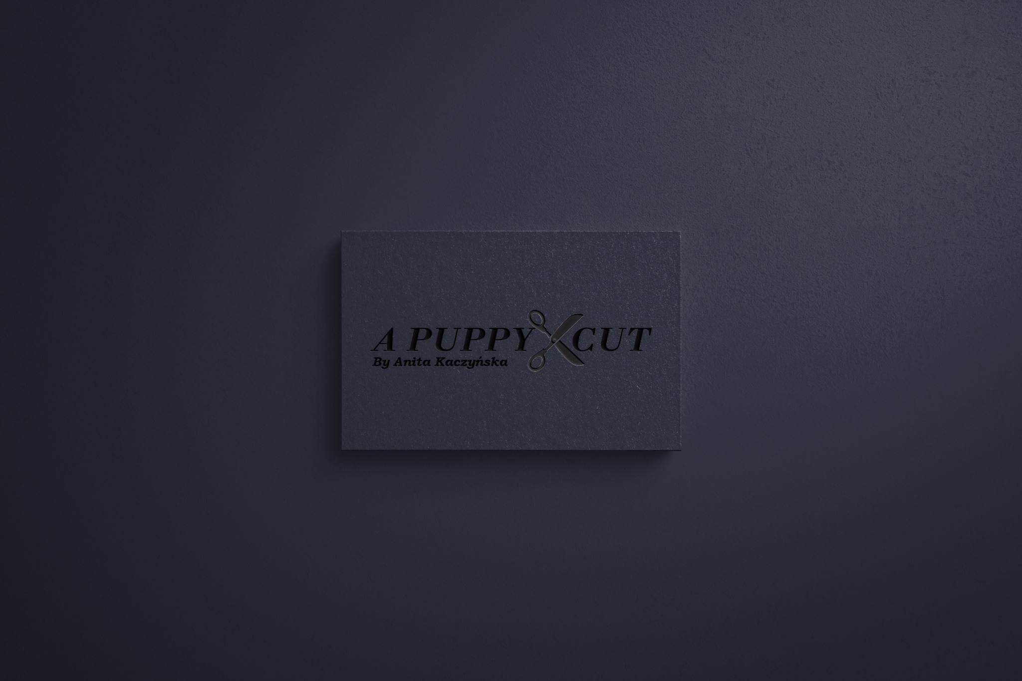 Elegancka wizytówka w odcieniach granatu z logo 'A Puppy Cut' i danymi kontaktowymi Anity Kaczyńskiej, z motywem nożyczek wkomponowanym w napis.