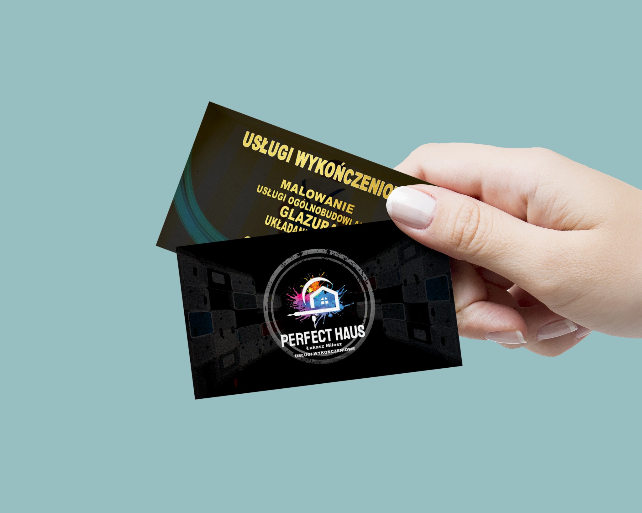 Dwie wizytówki firmy 'Perfect Haus' specjalizującej się w usługach wykończeniowych, trzymane w dłoni na jednolitym tle. Na jednej wizytówce wypisane usługi: malowanie, usługi ogólnobudowlane...