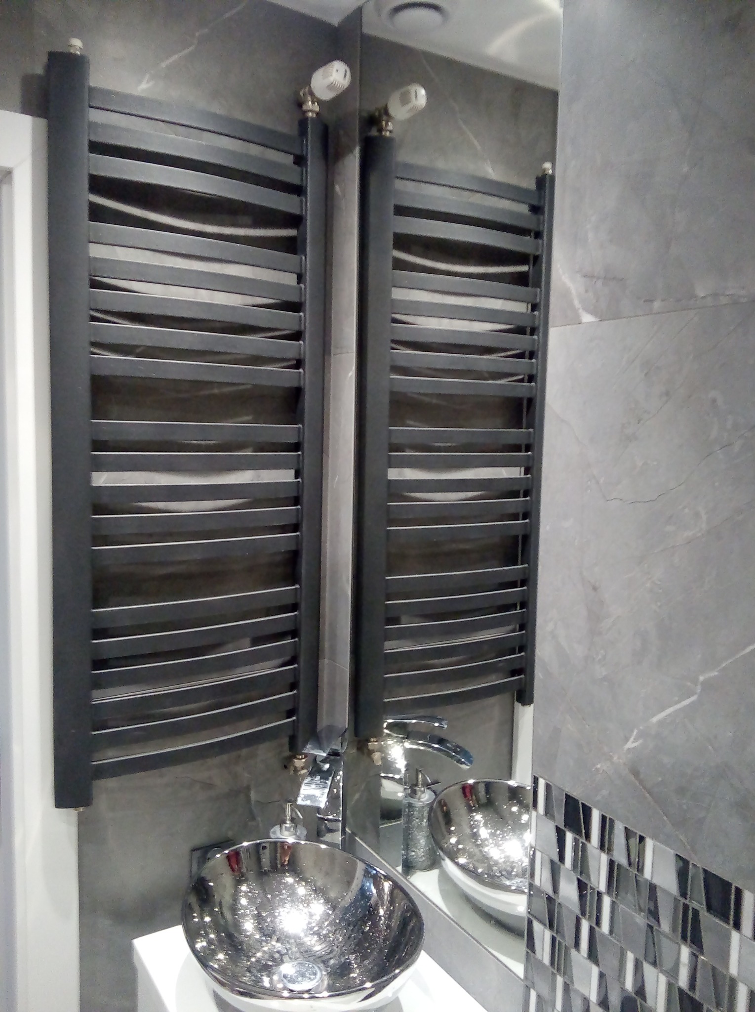 Nowoczesna łazienka z szarą marmurową ścianą, chromowaną umywalką nablatową i czarnym grzejnikiem drabinkowym.