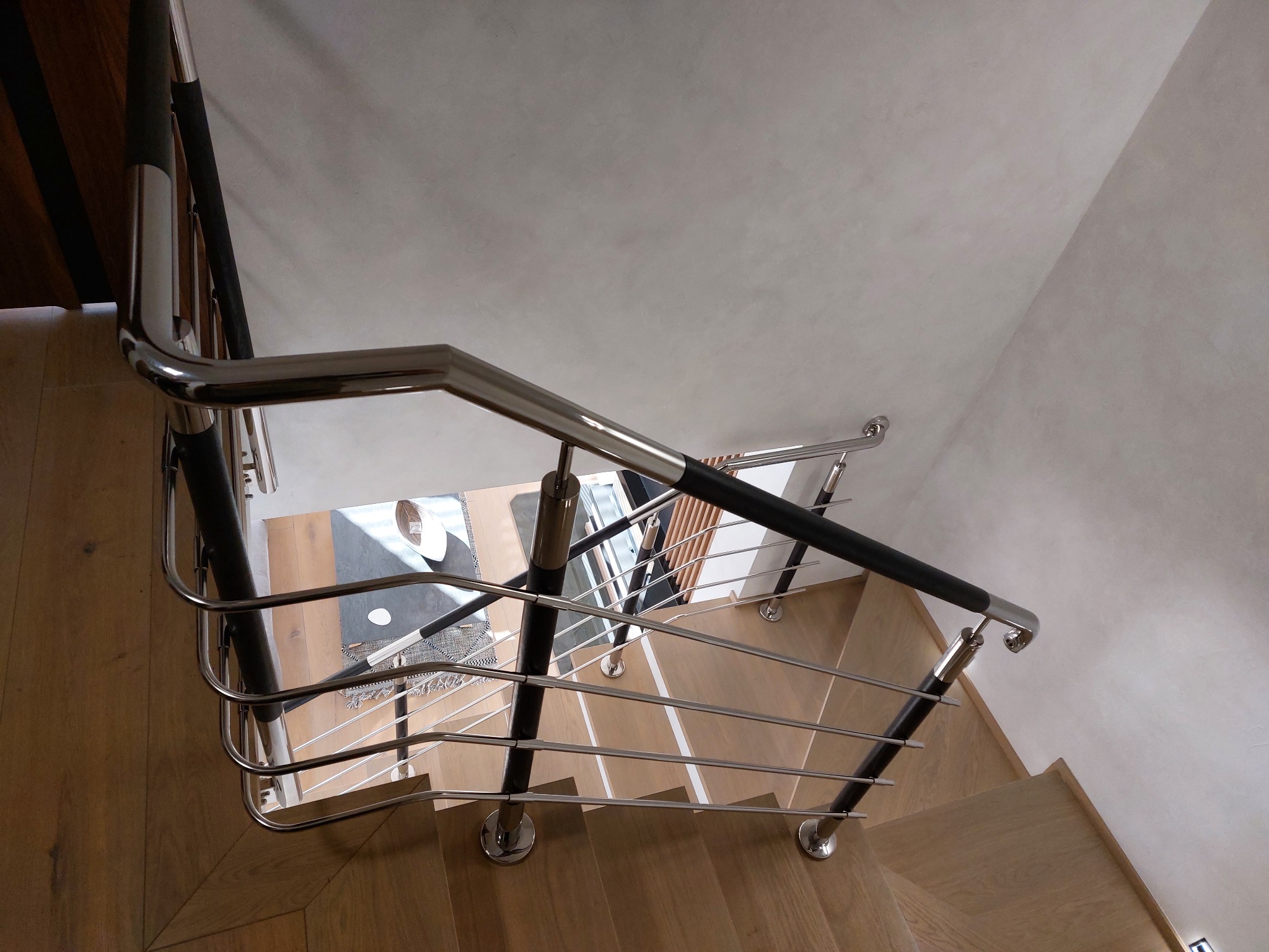 Schody drewniane z nowoczesną, metalową barierką z czarnymi elementami, widok z góry.