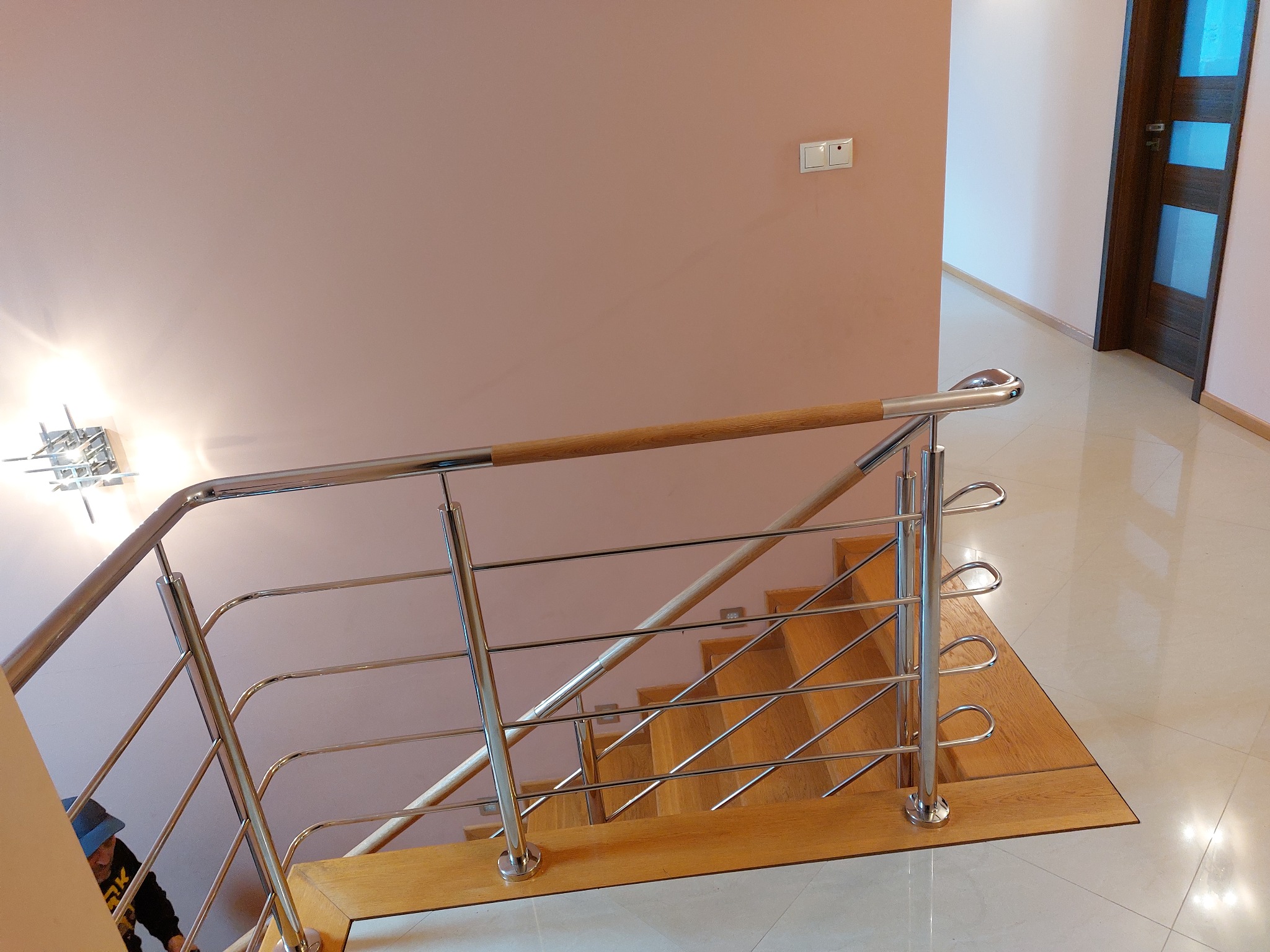 Wewnętrzna klatka schodowa z drewnianymi stopniami i chromowanymi balustradami z drewnianą poręczą, widok z góry.