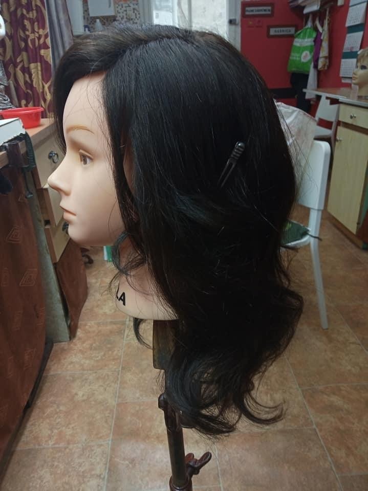 Peruka z długich, ciemnych, naturalnych włosów, wystylizowana na manekinie z widoczną spinką.