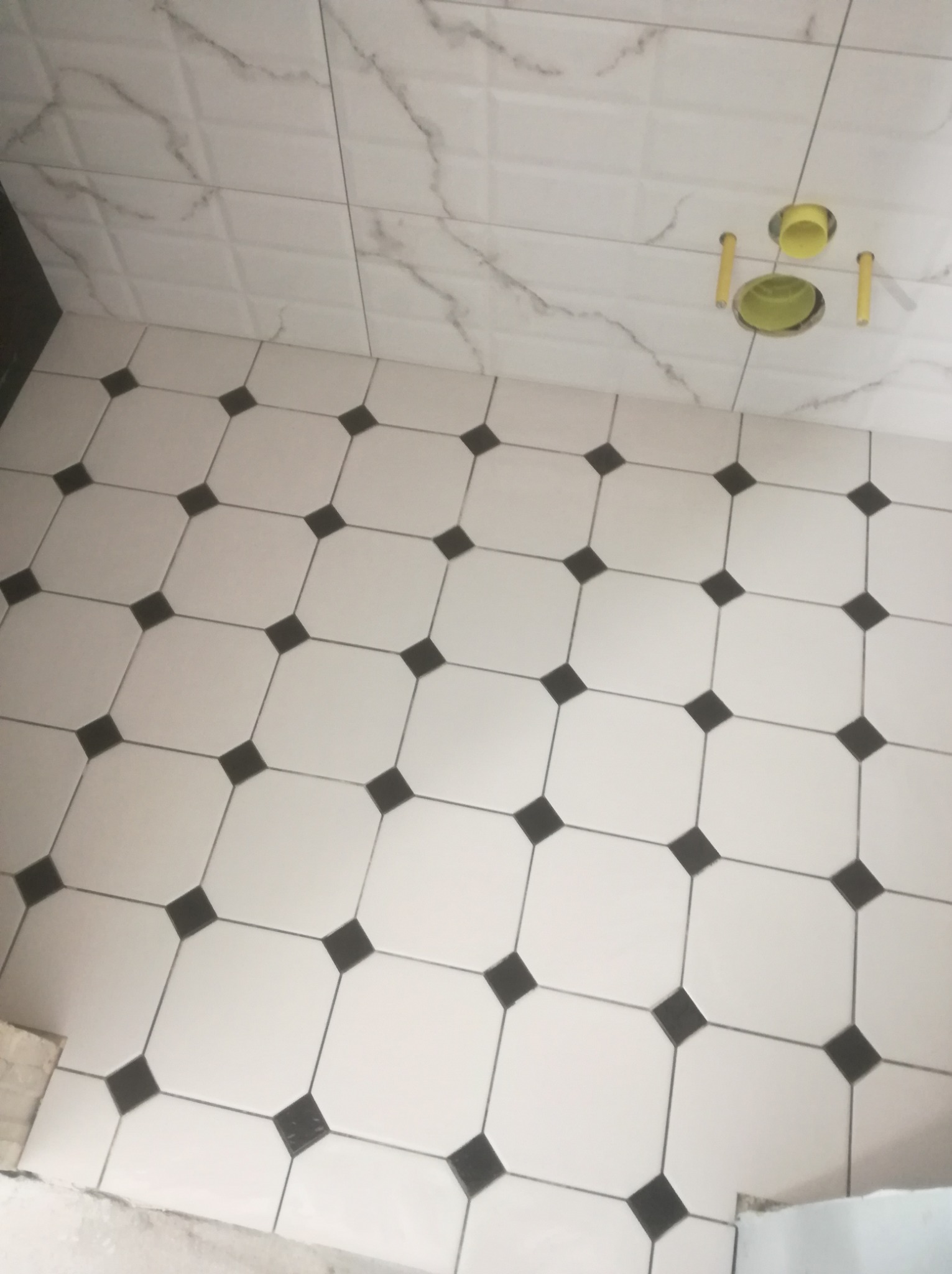 Przepiękne płytki podłogowe z charakterystycznymi czarnymi kwadracikami w niewielkiej łazience.