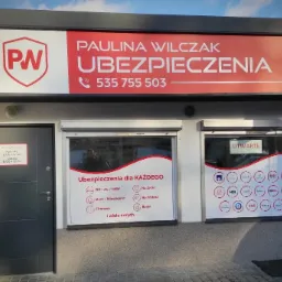 Fasada biura firmy ubezpieczeniowej Paulina Wilczak Ubezpieczenia z logo PW, numerem telefonu i informacją o godzinach otwarcia, okna z naklejkami informującymi o dostępnych rodzajach ubezpieczeń.