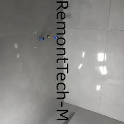 Świeżo ułożone, szare płytki podłogowe w łazience, z widocznym odpływem liniowym i elementami instalacji wodnej wystającymi ze ściany, zabezpieczonymi niebieską folią.