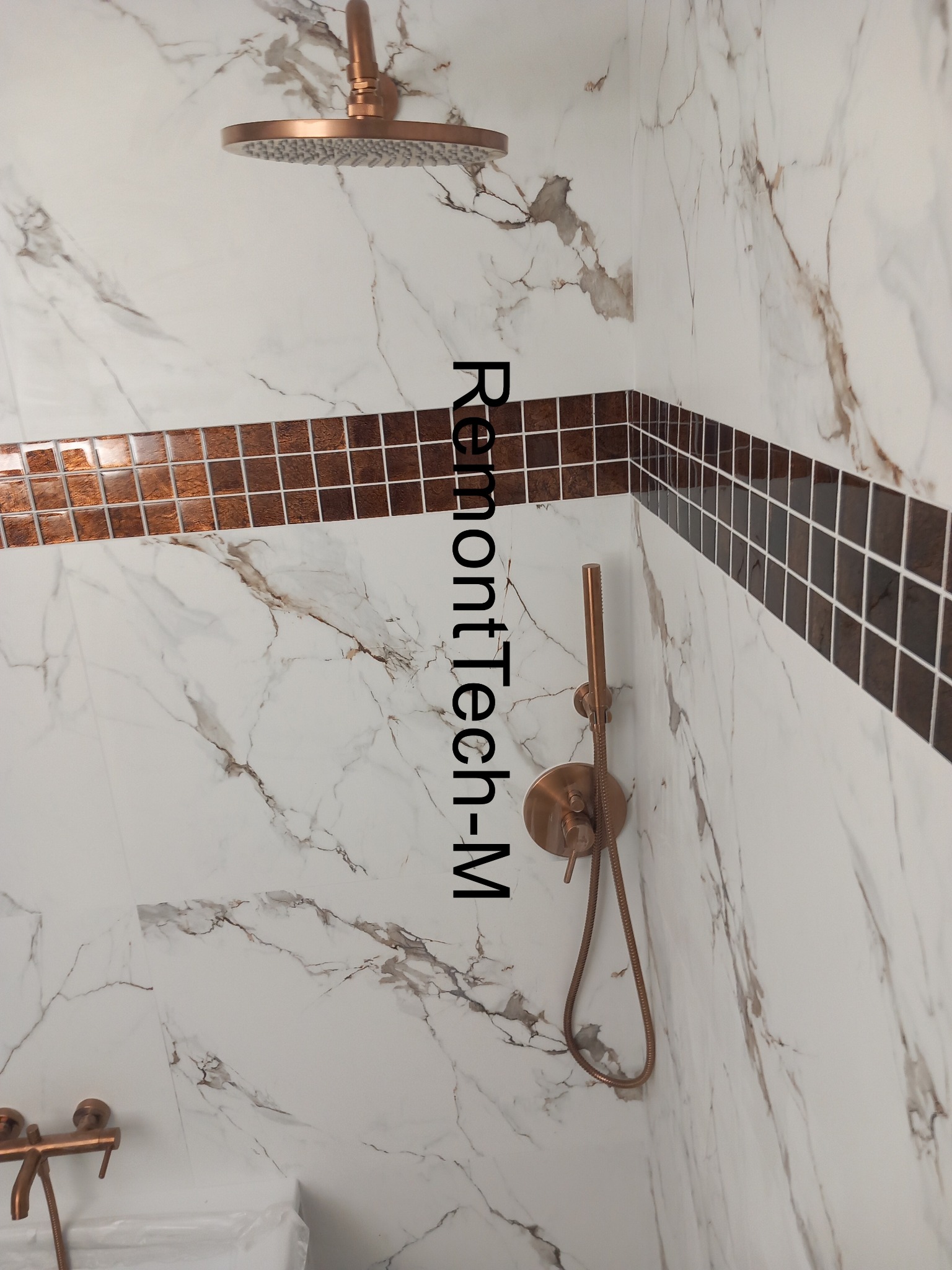 Wykończona łazienka z marmurowymi płytkami, mozaiką i miedzianą armaturą prysznicową. Nowoczesny design, eleganckie detale.