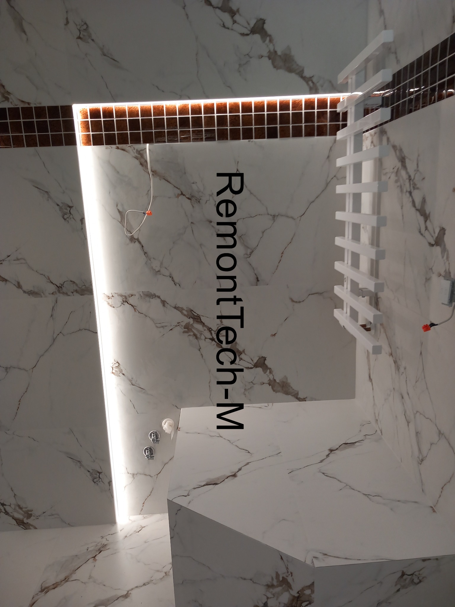 Wykończona łazienka z marmurowymi płytkami, podświetlanym lustrem i grzejnikiem drabinkowym. Widoczne detale wykończenia i oświetlenie.