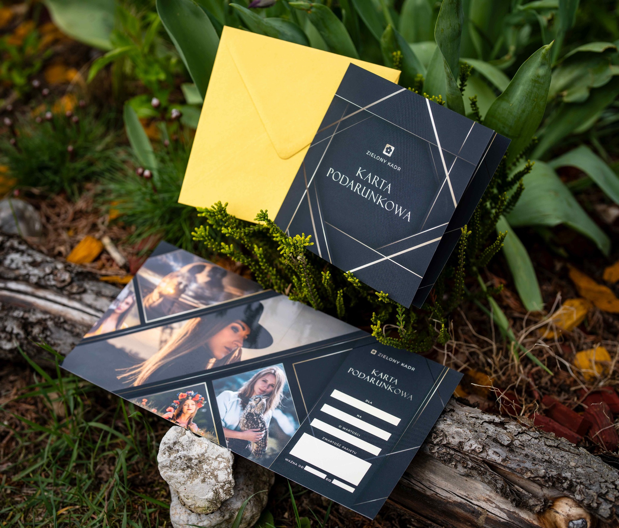 Karty podarunkowe 'Zielony Kadr' z żółtą kopertą na tle roślinności. Jedna karta z kolażem zdjęć, druga z miejscem na dane obdarowanego.
