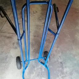 Dwa niebieskie, metalowe wózki transportowe z czarnymi uchwytami, wykonane we Wrocławiu, stoją na betonowej podłodze.