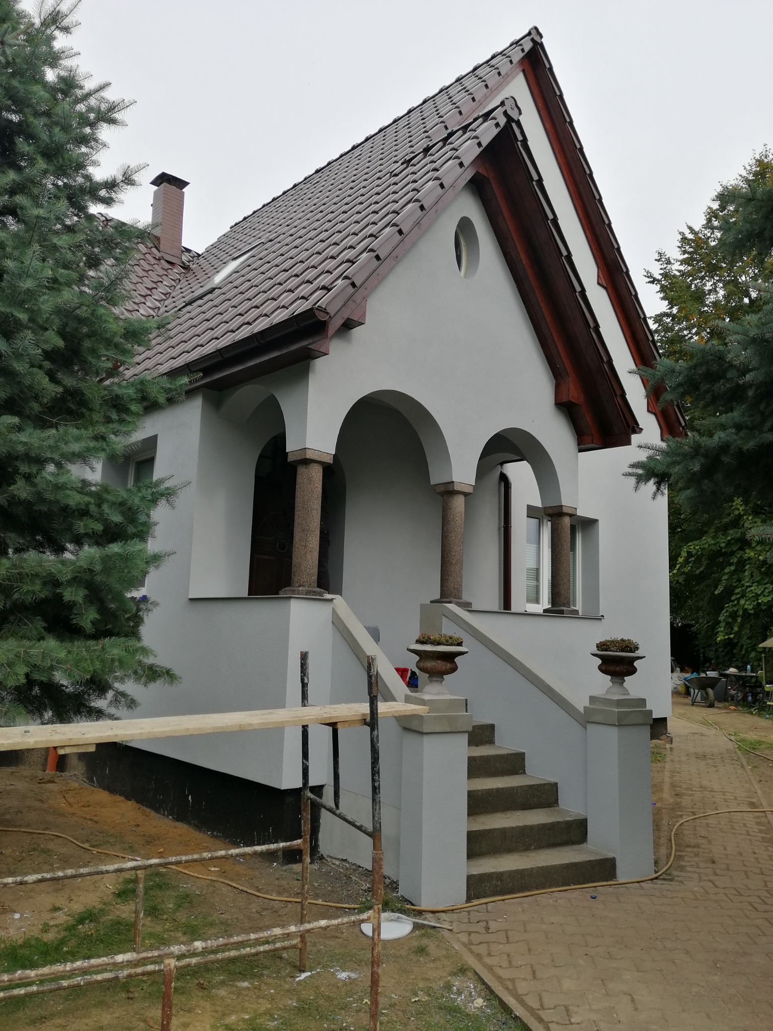 Szary dom jednorodzinny w Stargardzie z kolumnami przy wejściu i schodami, widoczne rusztowania sugerujące świeżo zakończone prace.