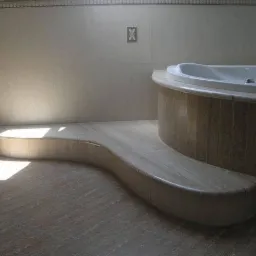 Wykończona łazienka z obudową wanny i podestem wykonanymi z jasnego kamienia naturalnego, z widocznym delikatnym wzorem słojów.