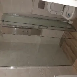 Wykończona kabina prysznicowa z hydromasażem i szklanymi drzwiami w łazience w Złotoryi, widok na toaletę i drewnopodobne płytki podłogowe.