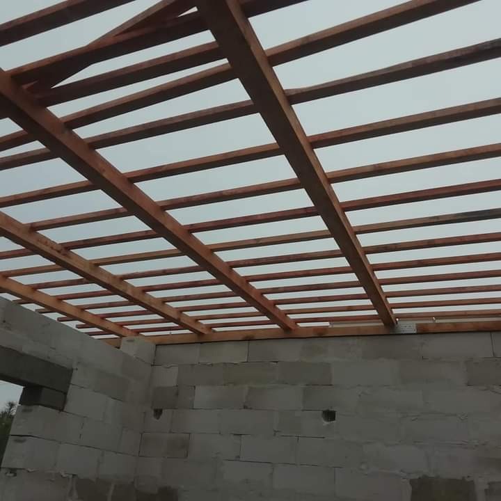 Konstrukcja drewniana dachu z belek na surowych ścianach z bloczków betonowych, widok z dołu.