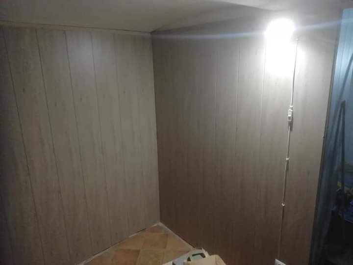 Wnętrze wykończone panelami ściennymi w odcieniach beżu i brązu, widoczna instalacja elektryczna z włącznikiem na ścianie, fragment podłogi z brązowych płytek.