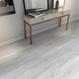 Express Remont - Jasnoszare panele podłogowe z widoczną strukturą drewna, ustawione prostopadle do ściany z niską konsolą i dekoracjami.