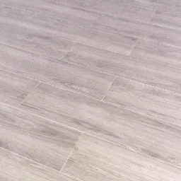 Ułożone diagonalnie jasnoszare płytki podłogowe imitujące drewno, z fugą w kolorze złamanej bieli.